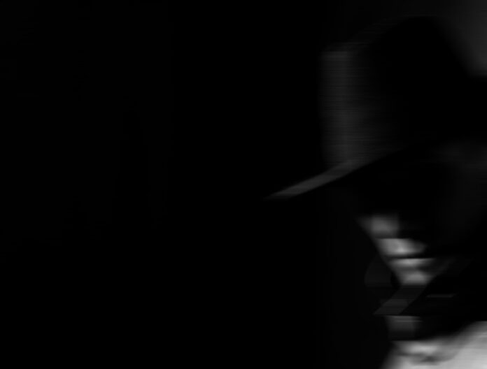 dark portrait of a man in a raincoat with a hat at night on the